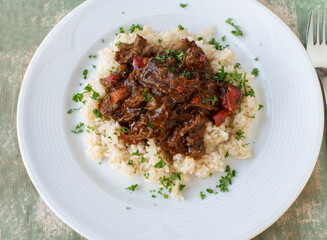 Wall Mural - Beef ragout with brown rice on a plate. Cooked with low fat and high protein meat - natural ingredients