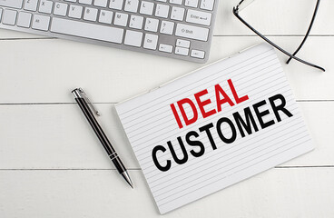 Poster - IDEAL CUSTOMER text on notebook with keyboard , pen glasses on white wooden background