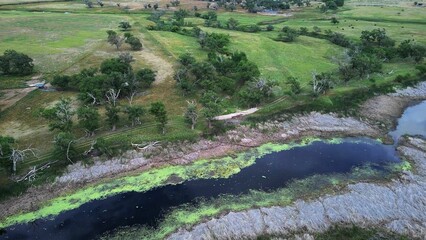 View of natural landscape of Tierra Blanca Creek with green lands and countryside houses in distance