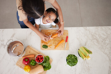 Canvas Print - Development, child and mother in kitchen, vegetables and learn cooking together being happy, smile and safety. Top view, mama and girl peeling food, childcare and cutting veggies and organic dinner.