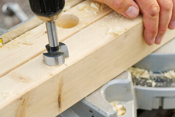 Wall Mural - Carpenter drilling holes in the wood beam. wooden frame domestic house building. drilling a hole with a handheld drill