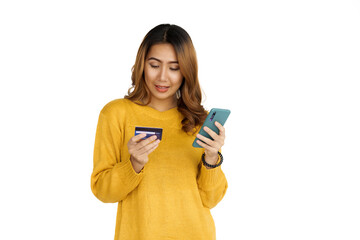 Attractive positive young asian brunette woman in yellow sweater on white background. Holding mobile and credit card