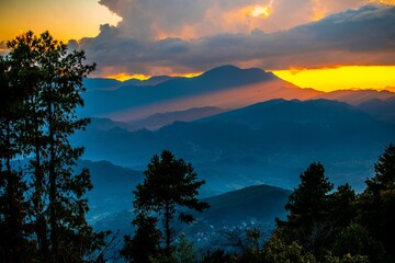 Poster - Mesmerizing soft orange sunset over the silhouette of hills with fluffy clouds in the sky