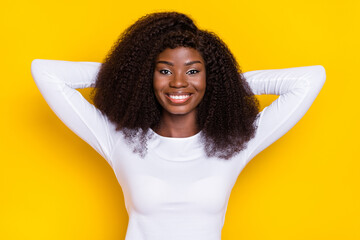 Wall Mural - Portrait of charming cheerful lady arms behind head toothy beaming smile isolated on yellow color background