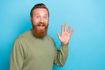 Wall Mural - Photo of sincere optimistic positive guy with ginger hairdo wear khaki long sleeve waving palm say hi isolated on blue color background