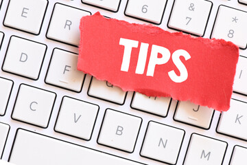 The word TIPS on a small red piece of paper lying on a computer keyboard.