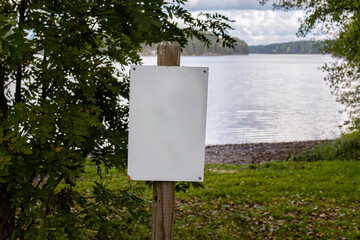 Empty white sign next to a beach in autumn