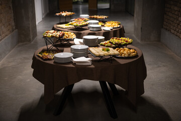 Cattering. Dark concrete business building hallway with table full of food.