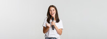 Beautiful Young Woman Singing Song In Microphone At Karaoke, Standing White Background