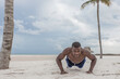 © Juanrastock - Black male doing push ups on beach