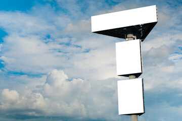 Wall Mural - three blank white billboards or large displays against blue sky with white clouds - mock up. consume