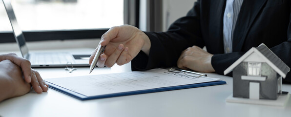 Wall Mural - An Asian female sales representative is discussing the details before the customer agrees to sign the contract. By explaining the details and terms and conditions of the rental real estate concept.