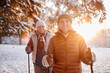 © Seventyfour - Waist up portrait of smiling mature couple enjoying Nordic walk in winter forest at sunset