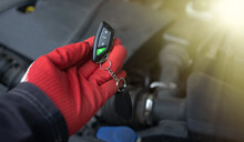 The master's hand holds a car alarm keychain. Installing an immobilizer in the car. Car security system. Keychain with buttons for the car.Sale of alarm systems for personal cars.