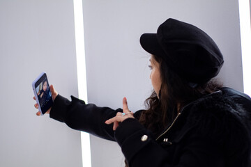 latina girl takes a selfie in a brightly lit aisle of a shopping mall.