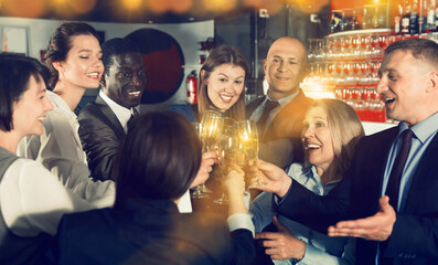 Wall Mural - International group of cheerful positive smiling businesspeople toasting with champagne, having fun at office party in nightclub