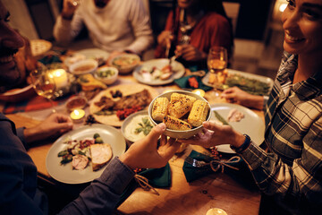 Wall Mural - Close up of couple passing food during Thanksgiving dinner at dining table.