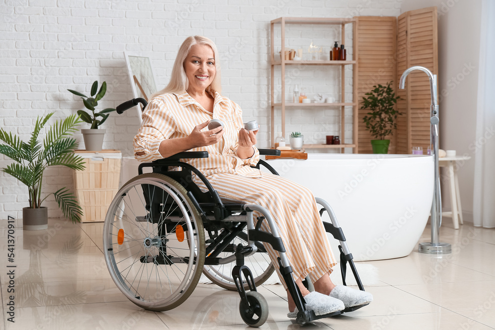 Mature woman with physical disability applying cream in bathroom