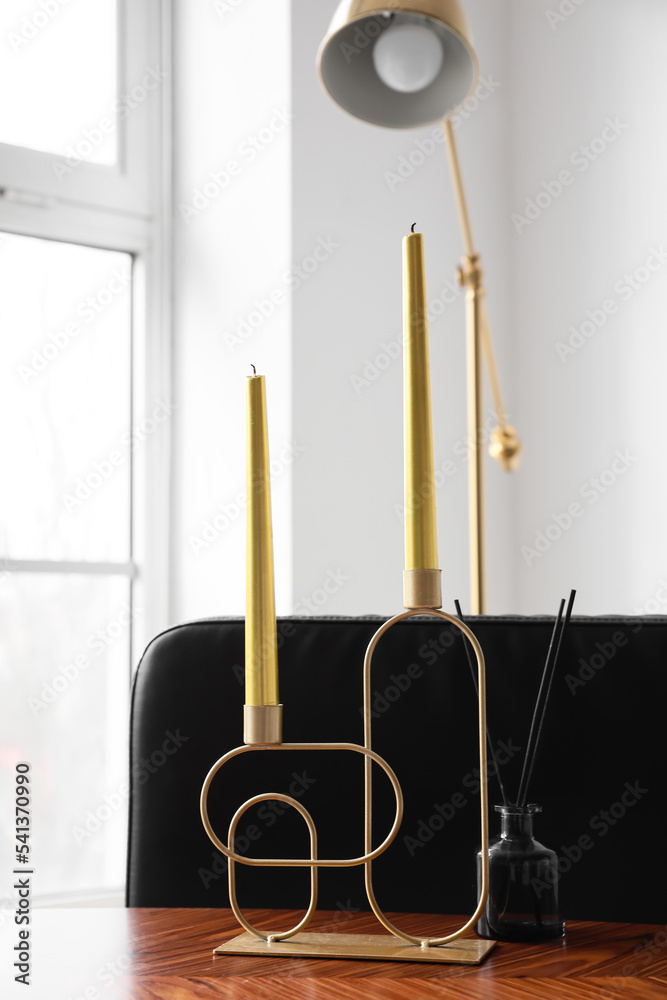 Stylish holder with candles and reed diffuser on wooden table