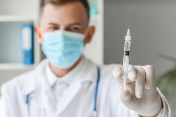 Wall Mural - Male doctor in medical mask with syringe at hospital, closeup