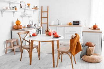 Poster - Interior of light kitchen with counters, dining table and pumpkins