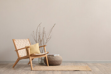 Interior of modern living room with wooden armchair, pouf and tree branches