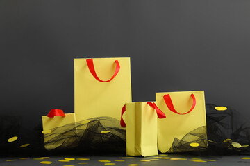Yellow shopping bags, veil and confetti on dark background. Black Friday sale