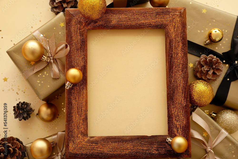 Blank frame with Christmas decor and presents on beige background