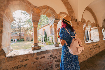 Wall Mural - A girl traveler and tourist in the arch of an ancient monastery or the courtyard of the cathedral
