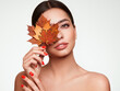 © Oleg Gekman - Portrait of beautiful young woman with autumn maple leafs. Healthy clean fresh skin natural make up beauty eyes and red nails