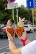 Vertical view of hands holding green and pink Taiyaki ice creams with cute dressings