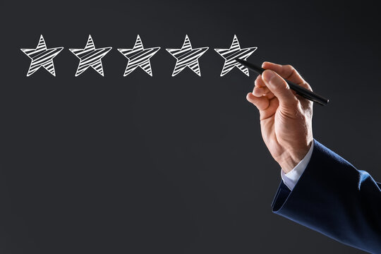 Man pointing at icons of five stars on dark grey background, closeup. Quality rating