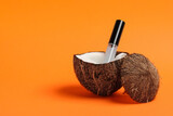 Fototapeta Sport - Tube of eyelash oil and fresh coconut on orange background. Space for text