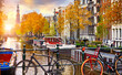 Bike over canal Amsterdam city autumn yellow leaf fall. Picturesque town landscape in Netherlands with view on river Amstel.