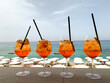 4 kolorowe drinki na tle nadmorskiej plaży