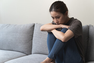 Wall Mural - Unhappy anxiety young Asian woman covering her face with pillow on the cough in the living room at home.