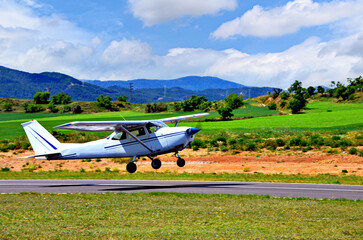 Wall Mural - Single engine ultralight airplane taking off from airfield under blue sky with white clouds	