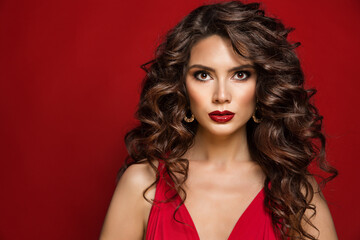 Wall Mural - Brunette Beauty Woman with Black Curly Hair and Perfect Red Lips Make up. Fashion Model with Wavy Long Hairstyle and Smooth Skin Makeup over Red Background