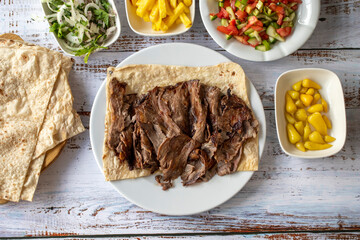 Wall Mural - Turkish meat doner on wood background. Traditional flavors. Doner kebab made from beef and lamb. Top view