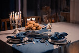 Fototapeta Łazienka - Food for Hanukkah celebration: Menorah Candles on wooden table, sufganiyot cake and table setting, jewish symbol centerpieces, white and blue. holiday Israel hebrew traditional family celebration