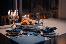 Food For Hanukkah Celebration: Menorah Candles On Wooden Table, Sufganiyot Cake And Table Setting, Jewish Symbol Centerpieces, White And Blue. Holiday Israel Hebrew Traditional Family Celebration