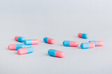 Fototapeta Mapy - Heap of pink and blue pills on colored background. Tablets scattered on a table. Pile of red soft gelatin capsule. Vitamins and dietary supplements concept