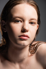 Wall Mural - Young model with wet hair and water drops on neck looking at camera isolated on grey