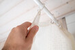 Hand closes a waterproof curtain in the bathroom, which covers the shower and prevents moisture from entering the floor. Bottom view. 