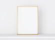 Interior poster mockup with vertical golden metal frame on white wall . A4, A3 size format. 3D rendering, illustration.