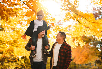 Wall Mural - Happy two man couple with adopted child on autumn season