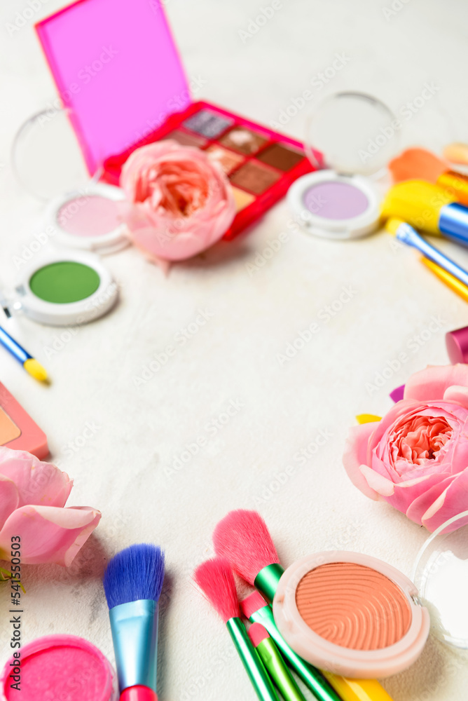 Decorative cosmetics, brushes and flowers on light background