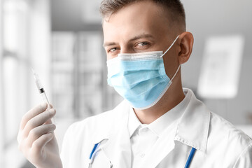 Wall Mural - Male doctor in medical mask with syringe at hospital, closeup