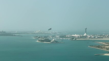 Wall Mural - United Arab Emirates flag waving around Abu Dhabi city landmarks - Aerial high view of the capital of UAE - corniche towers