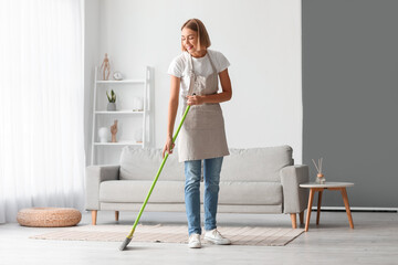 Wall Mural - Young housewife mopping floor at home